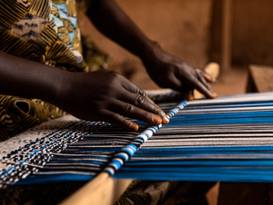 Artisan burkinabè tissant le Faso Dan Fani sur un métier traditionnel — un savoir-faire authentique transmis de génération en génération.